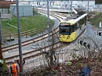 On the first day, rail workers look on as tram 3022 slowly rounds the new curve back onto the original route to Manchester and beyond 27/01/2014. Photo R Clarke